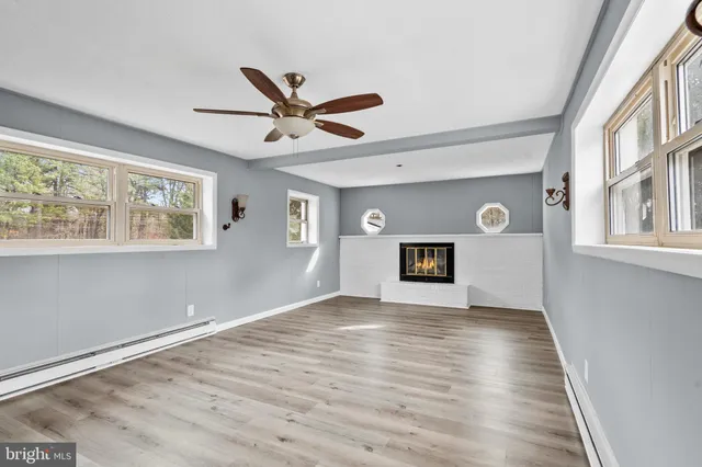 a view of an empty room with a window and wooden floor