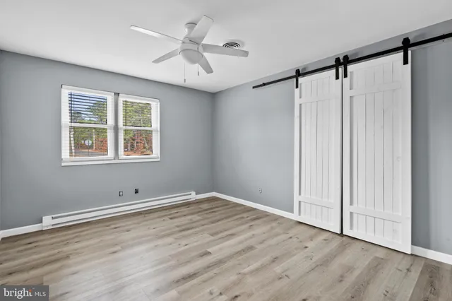 a view of empty room with wooden floor and fan