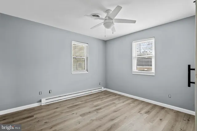 a view of a big room with wooden floor and windows