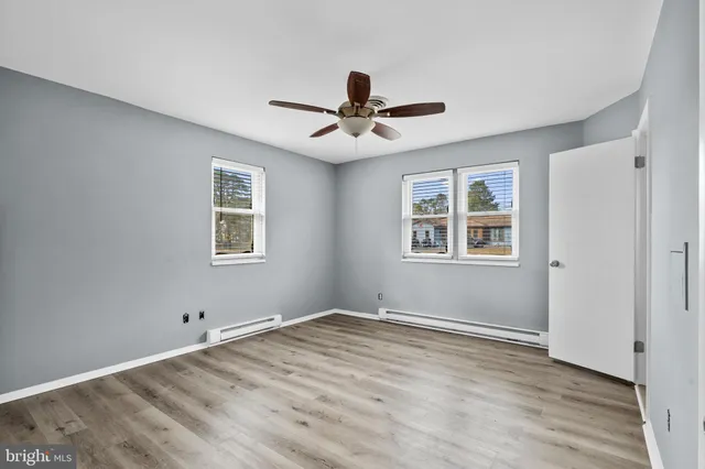 a view of empty room with wooden floor and ceiling fan