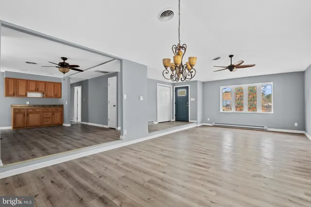 a view of an empty room with wooden floor and a ceiling fan