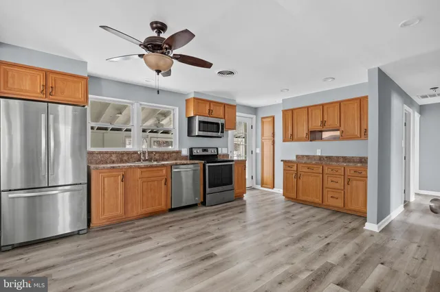 a kitchen with granite countertop stainless steel appliances a refrigerator cabinets and wooden floor