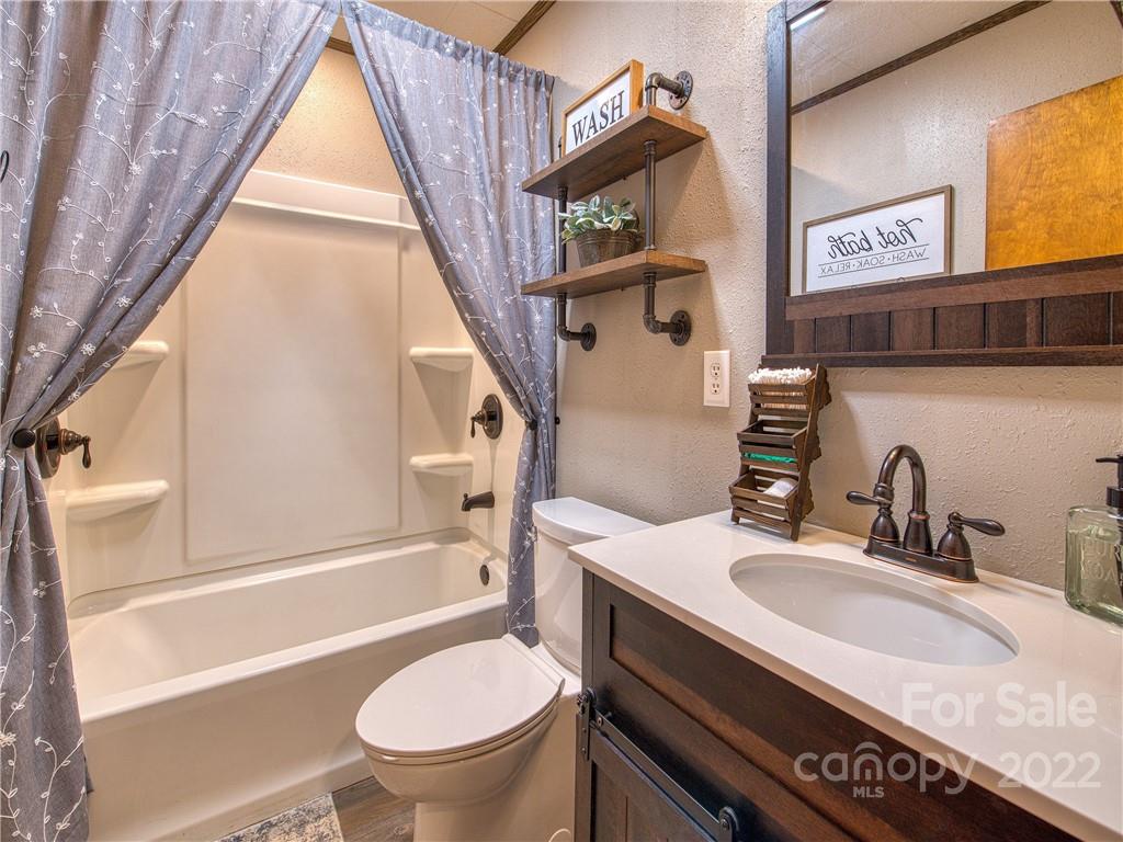 1239 Beaverdam Road Canton, NC 28716 - Photo 17 of 30 a bathroom with a granite countertop sink toilet and a bathtub