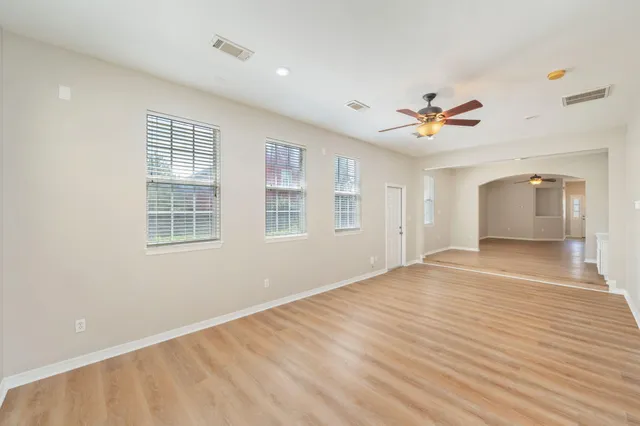 a view of an empty room with a window and wooden floor