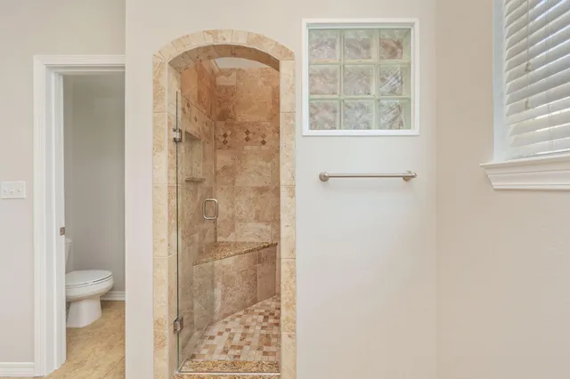 a bathroom with a granite countertop shower a mirror and a toilet