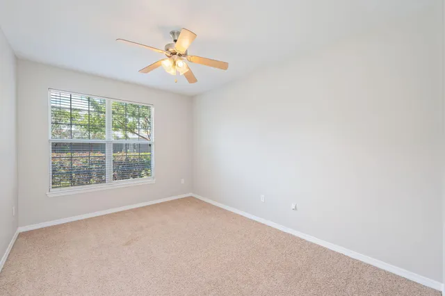 an empty room with a window and a fan