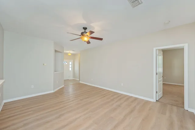 an empty room with wooden floor and chandelier fan