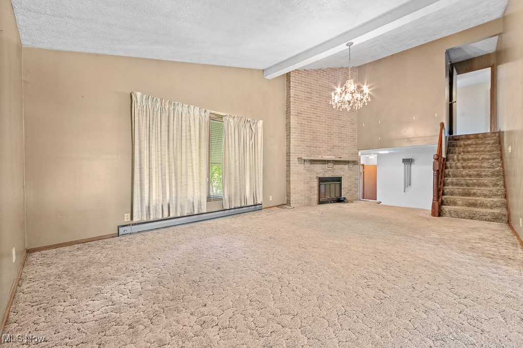 1165 Homeworth Road Alliance, OH 44601 - Photo 14 of 36 Unfurnished living room featuring lofted ceiling with beams, carpet flooring, a baseboard radiator, and an inviting chandelier