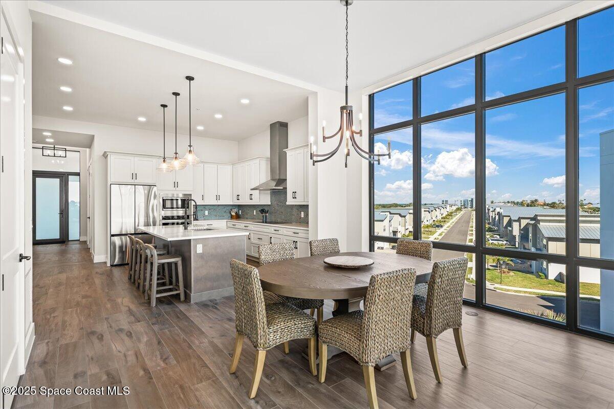 225 Strand Drive, Unit 401 Melbourne Beach, FL 32951 - Photo 7 of 51 a dining room with stainless steel appliances granite countertop a stove top oven a dining table and chairs with wooden floor