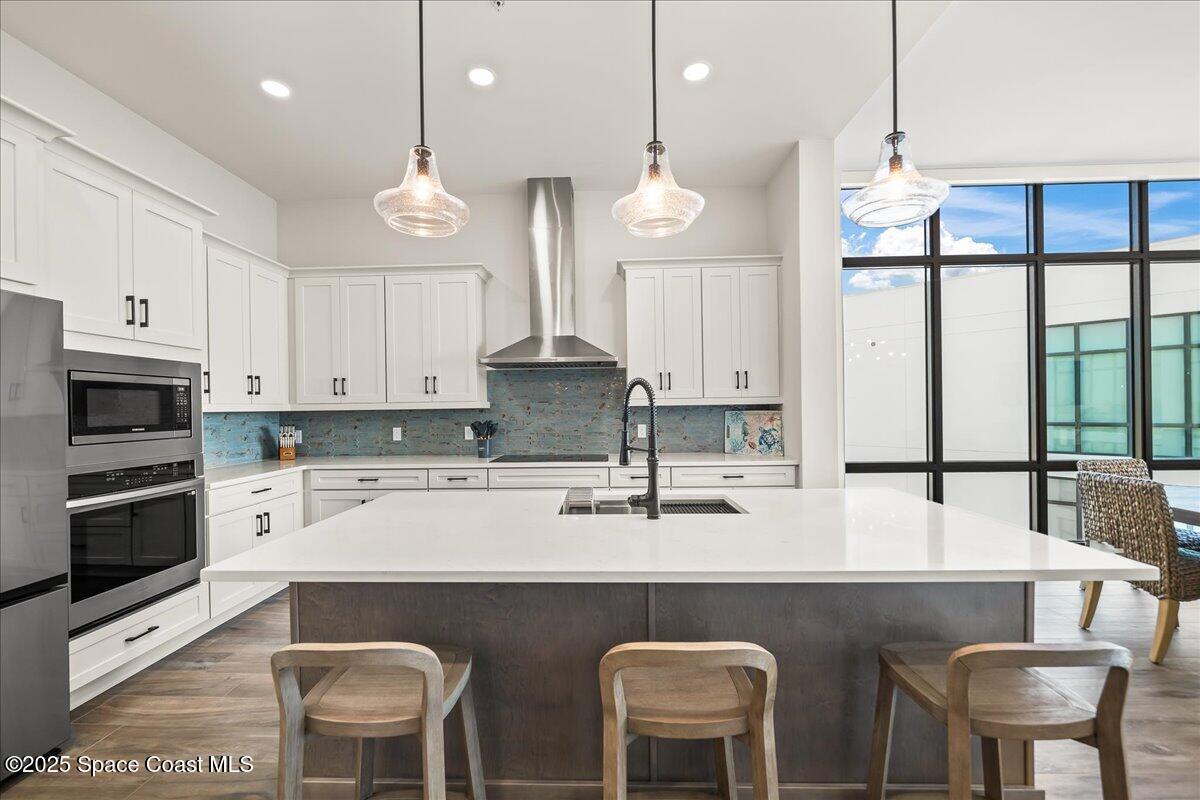 225 Strand Drive, Unit 401 Melbourne Beach, FL 32951 - Photo 8 of 51 a kitchen with stainless steel appliances granite countertop a stove a refrigerator a sink a dining table and chairs with white cabinets