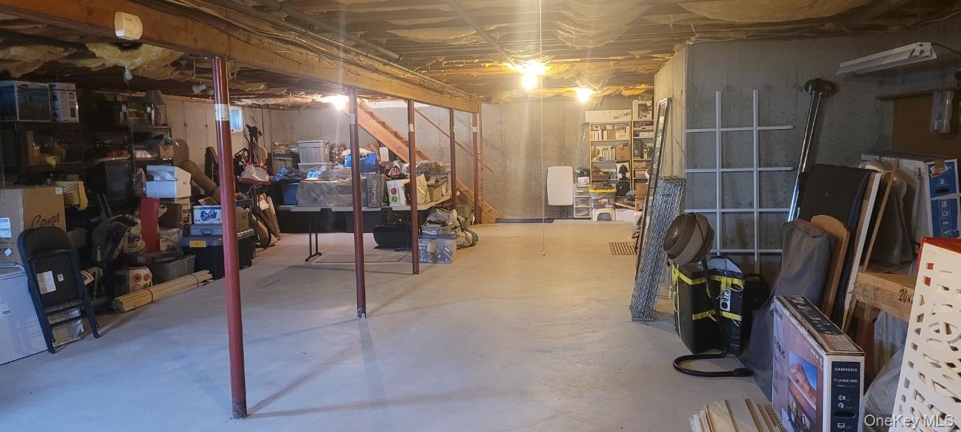 312 Riley Avenue Calverton, NY 11933 - Photo 17 of 30 Unfinished basement with concrete flooring, exposed high ceiling joists, and structural support beams