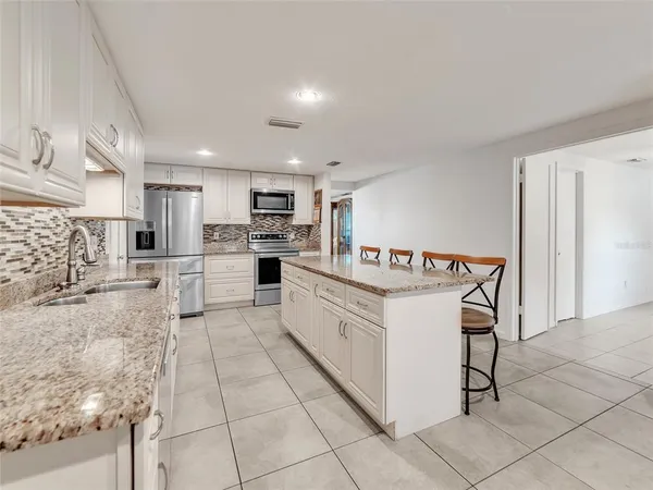 a kitchen with stainless steel appliances kitchen island granite countertop a refrigerator and a stove top oven