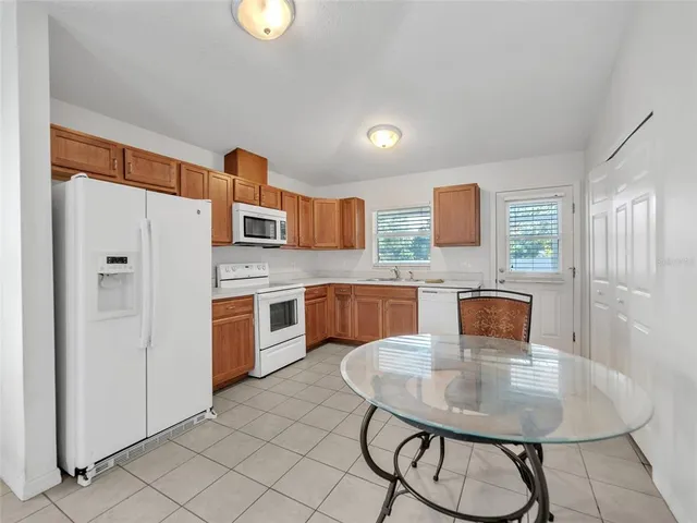 a kitchen with stainless steel appliances granite countertop a sink a stove a refrigerator with a dining table and chairs