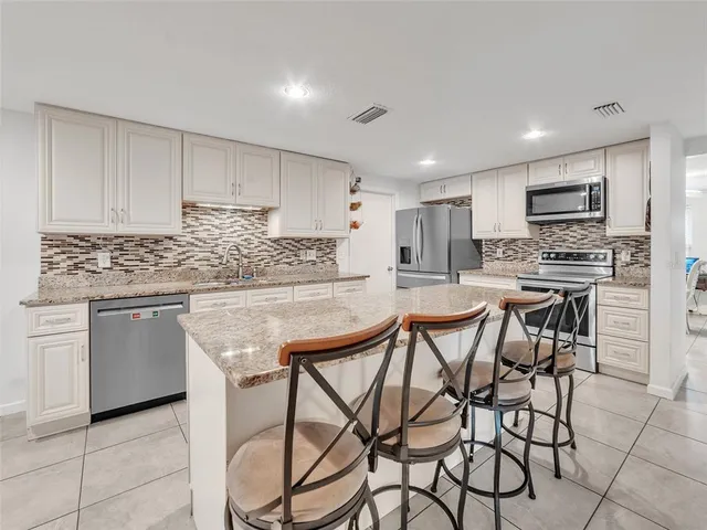 a kitchen with kitchen island granite countertop wooden cabinets and stainless steel appliances
