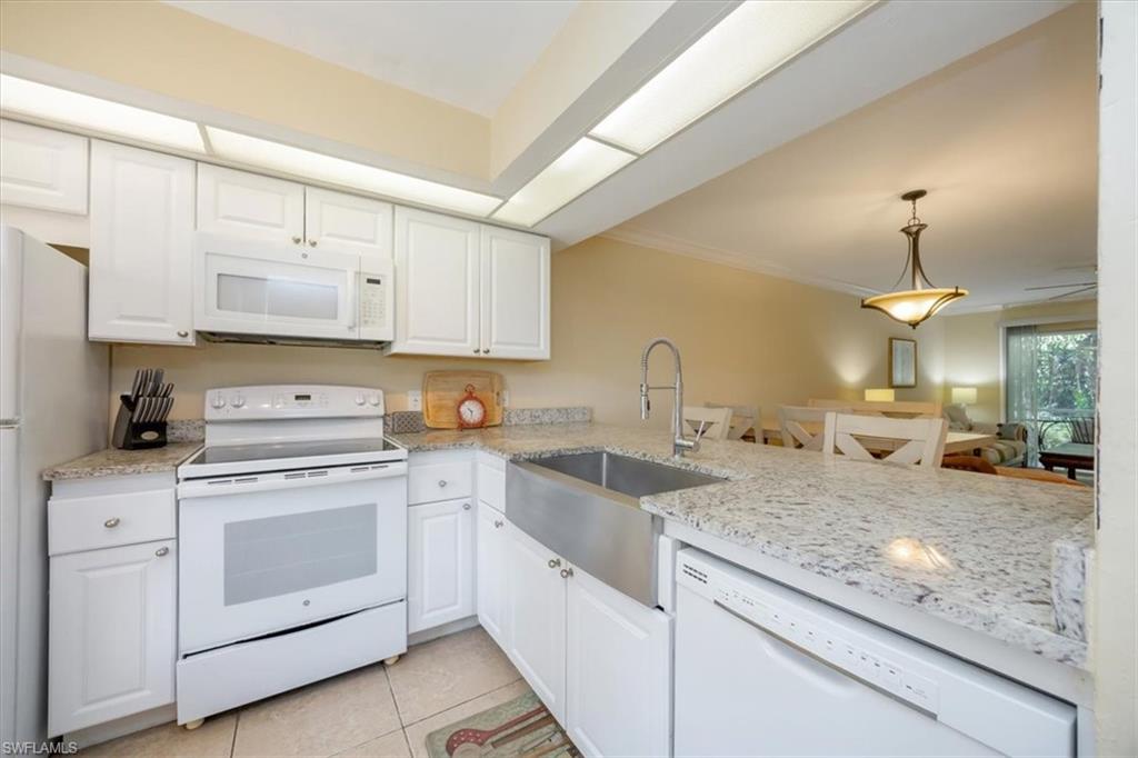 338 Bradstrom Circle, Unit 102 Naples, FL 34113 - Photo 9 of 21 a kitchen with granite countertop white cabinets and white appliances