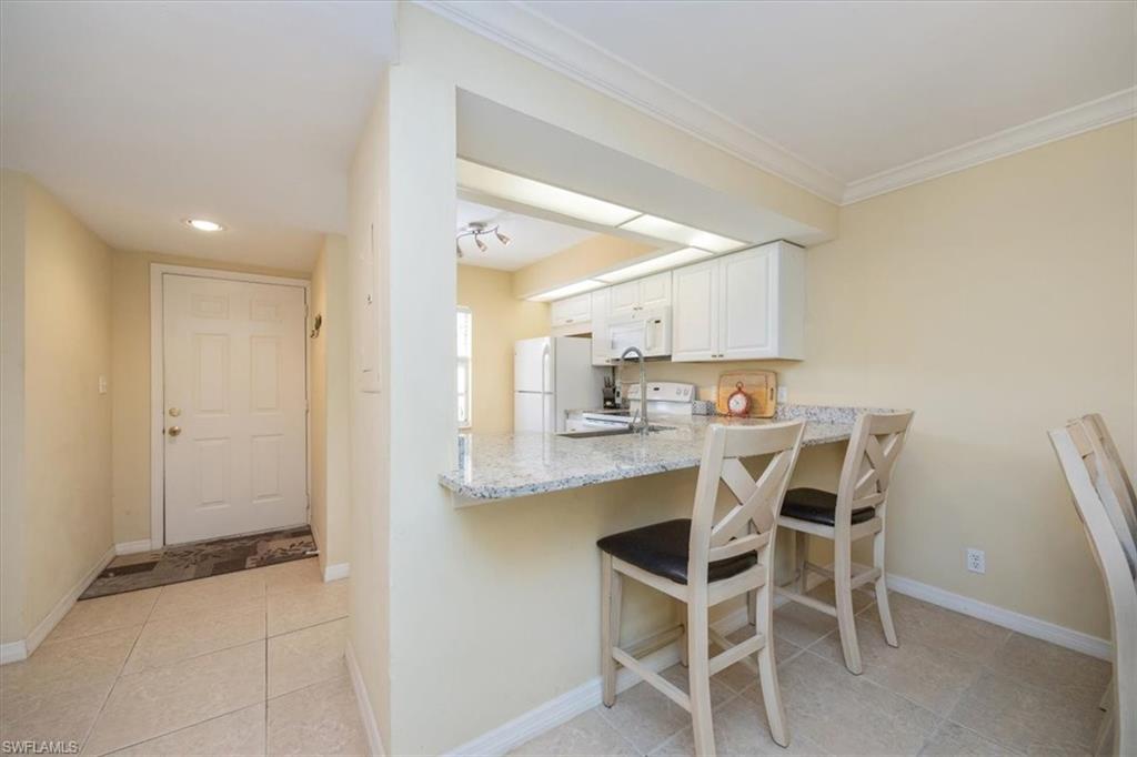 338 Bradstrom Circle, Unit 102 Naples, FL 34113 - Photo 10 of 21 a kitchen with a dining table chairs cabinets and stainless steel appliances