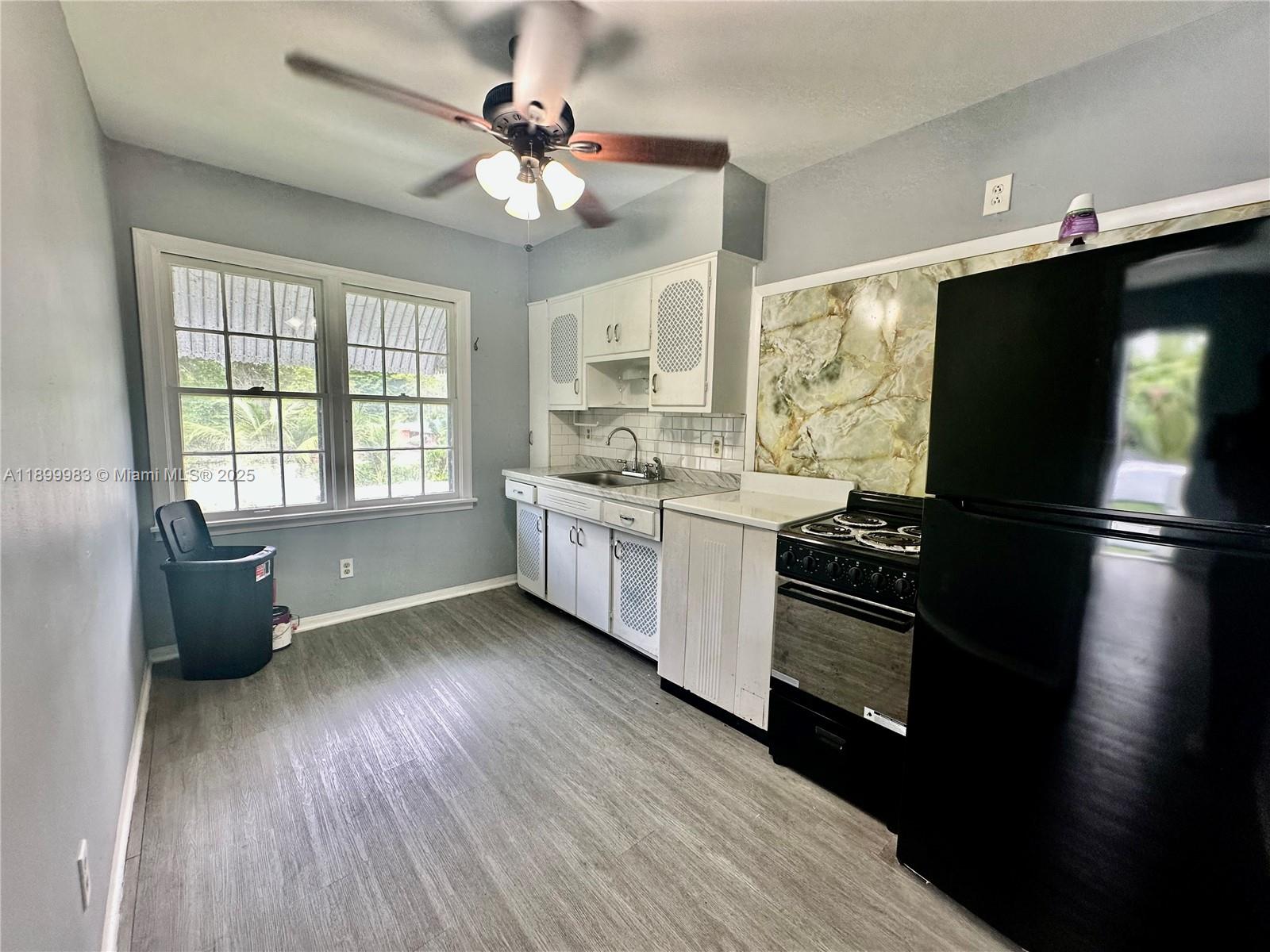 1260 Northeast 115th Street, Unit 2 Miami, FL 33161 - Photo 2 of 9 a kitchen with stainless steel appliances granite countertop a refrigerator a sink dishwasher a stove and white countertops with wooden floor