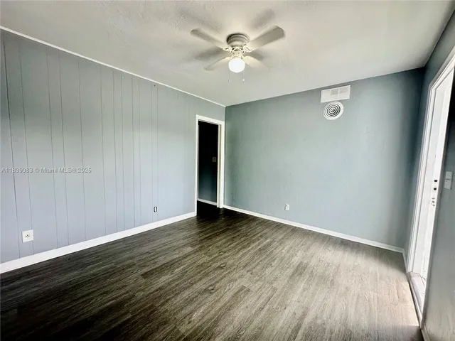 an empty room with wooden floor and fan