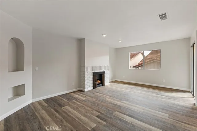 a view of empty room with wooden floor and fireplace
