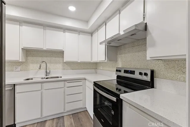 a kitchen with stainless steel appliances a sink dishwasher stove and white cabinets