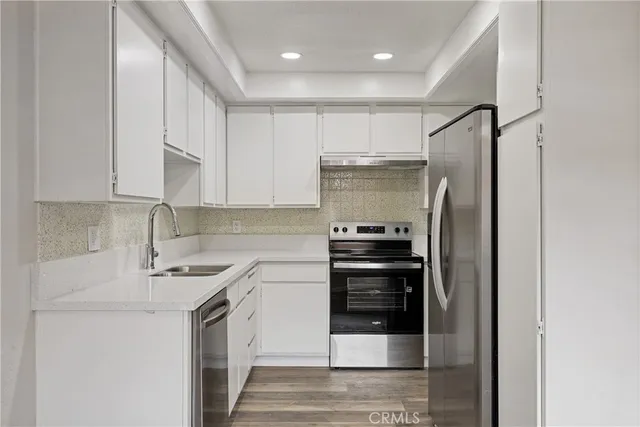 a kitchen with stainless steel appliances a refrigerator a stove and white cabinets
