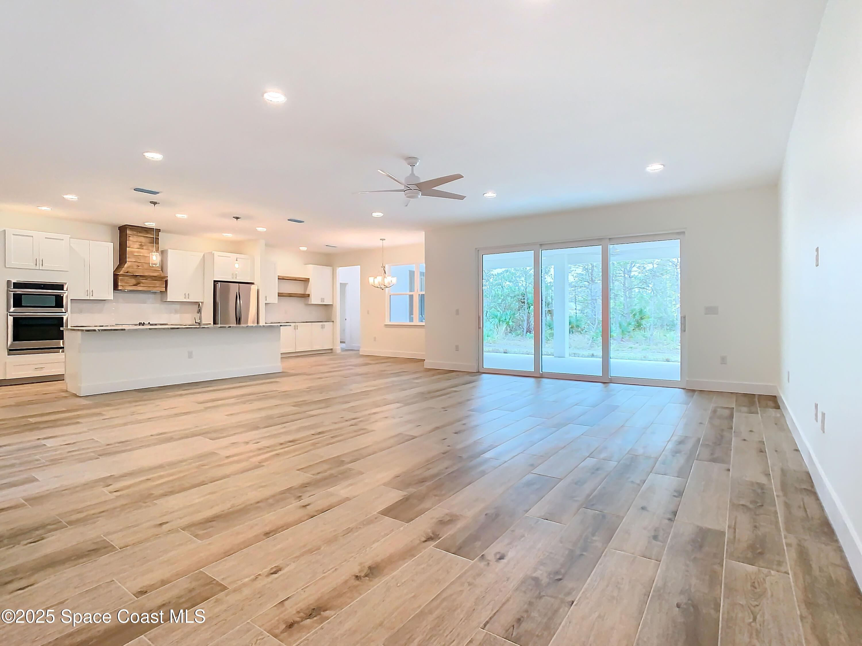 6110 Brabrook Avenue Grant, FL 32949 - Photo 11 of 85 a view of an empty room and kitchen with wooden floor and window