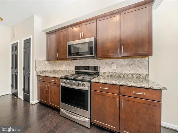 a kitchen with granite countertop wooden cabinets and stainless steel appliances