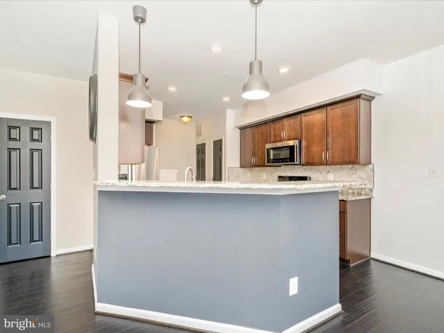a view of a kitchen with stainless steel appliances granite countertop a stove a sink and a wooden floors