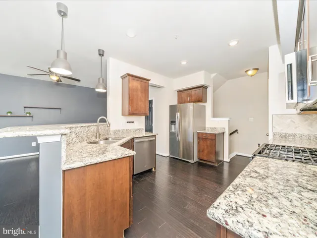 a kitchen with stainless steel appliances granite countertop a sink dishwasher and a stove with wooden floor