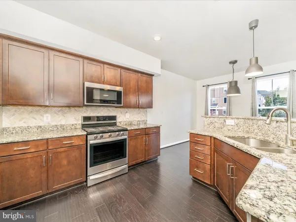 a kitchen with stainless steel appliances granite countertop a sink a stove a microwave and wooden floors