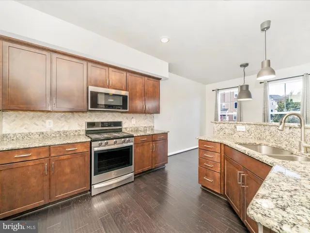 a kitchen with stainless steel appliances granite countertop a sink a stove a microwave and wooden floors