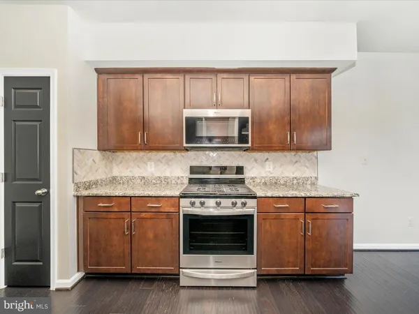 a kitchen with granite countertop a stove microwave and sink