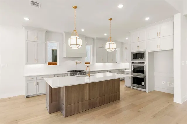a large kitchen with kitchen island a sink stainless steel appliances and cabinets
