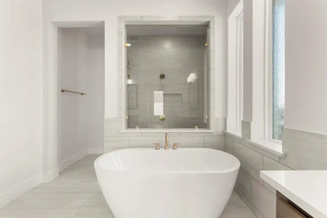 a white bath tub sitting in a bathroom next to a window