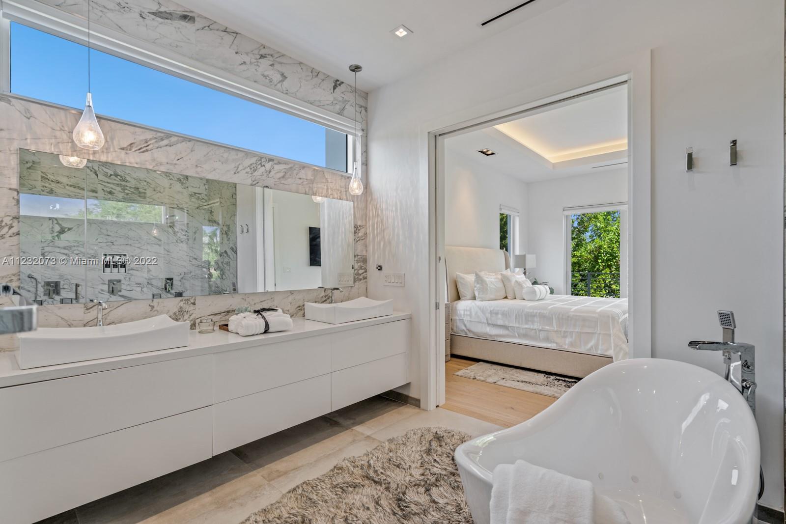 4610 Alton Road Miami Beach, FL 33140 - Photo 15 of 38 a en suite bathroom with a double vanity sink and mirror