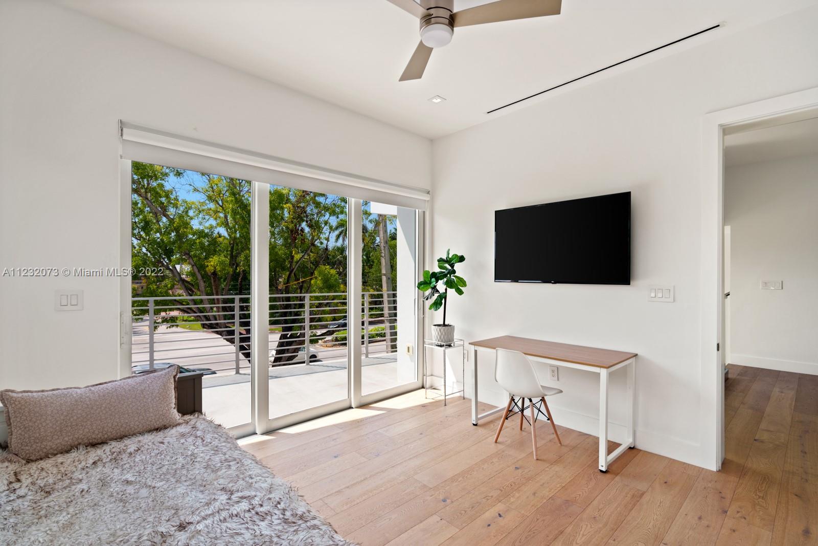 4610 Alton Road Miami Beach, FL 33140 - Photo 24 of 38 a living room with furniture a flat screen tv and a floor to ceiling window
