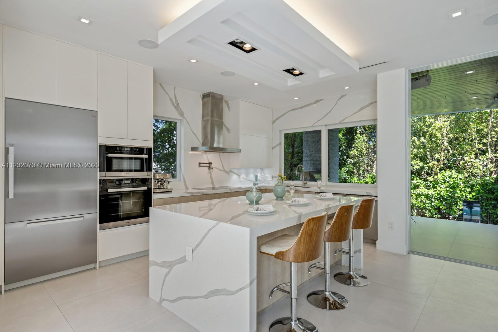 4610 Alton Road Miami Beach, FL 33140 - Photo 7 of 38 a kitchen with stainless steel appliances kitchen island granite countertop a refrigerator and a stove top oven