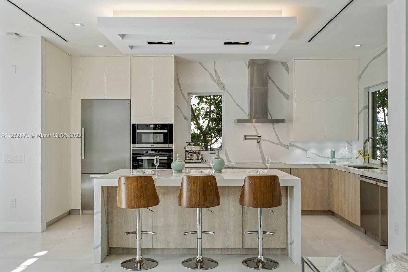 4610 Alton Road Miami Beach, FL 33140 - Photo 9 of 38 a kitchen with stainless steel appliances kitchen island granite countertop a table and chairs in it