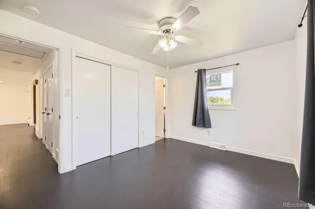 an empty room with wooden floor chandelier fan and windows