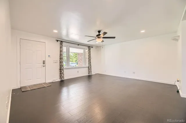 an empty room with windows and ceiling fan