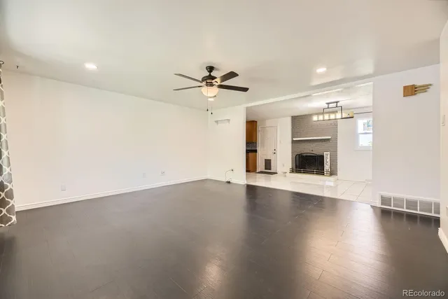 an empty room with wooden floor and ceiling fan