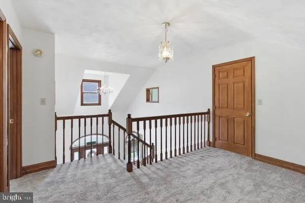 a view of a hallway with windows and chandelier