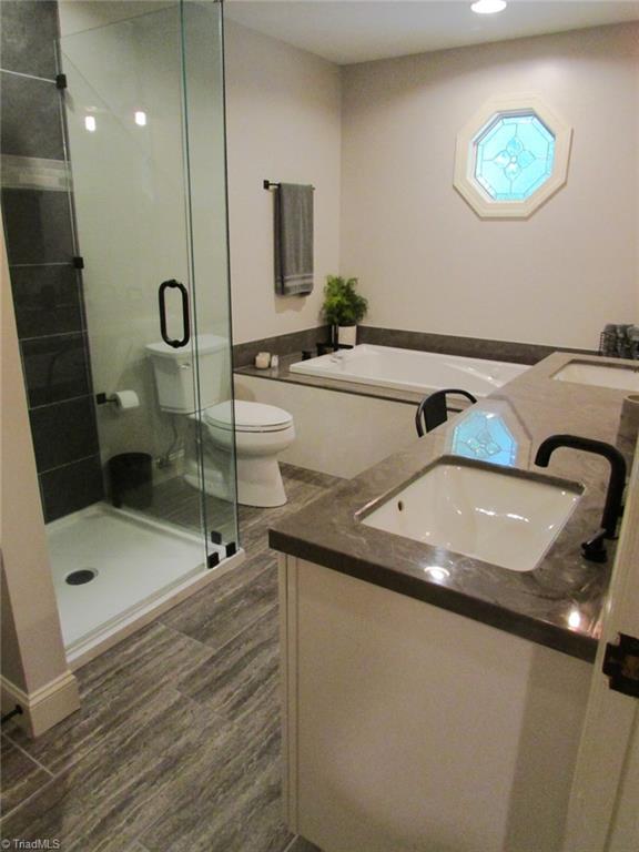 7232 Ledbetter Road Climax, NC 27233 - Photo 22 of 33 Newly Remodeled Master Ensuite Bath Features Deep Soaking Tub, Separate Tile Shower, Double Sinks, Make-Up Vanity Space, Wood Look Tile Flooring & Linen Closet