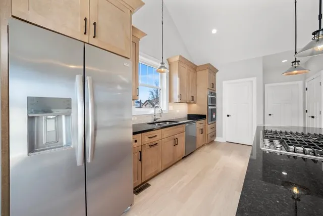 a kitchen with stainless steel appliances kitchen island granite countertop a refrigerator a sink and white cabinets