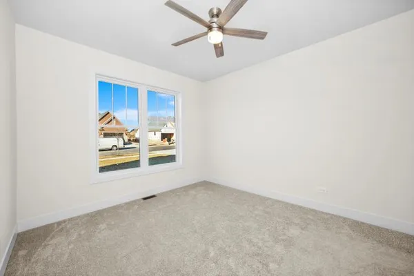 an empty room with a window and ceiling fan