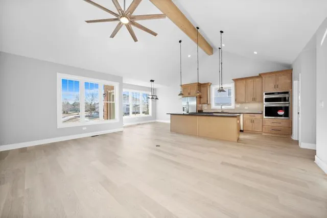 a view of an empty room with kitchen and window