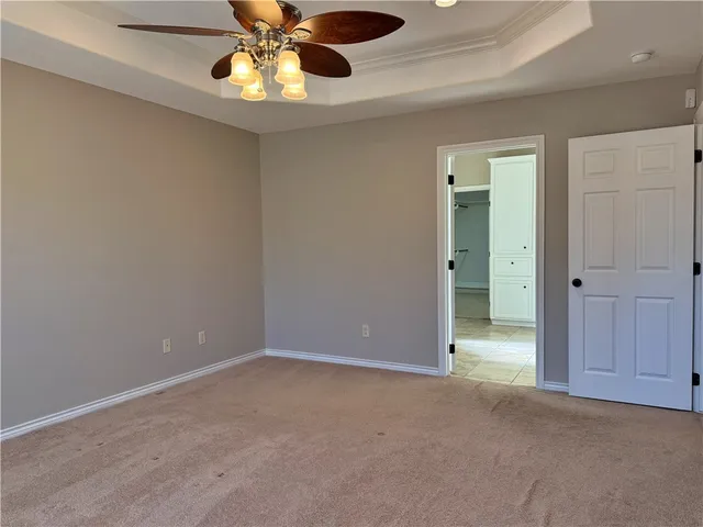 a view of an empty room and chandelier fan