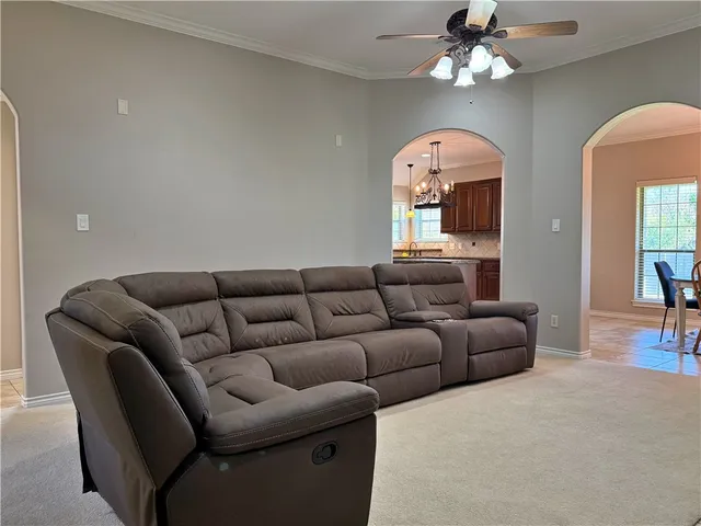a living room with furniture a ceiling fan a window and a chandelier