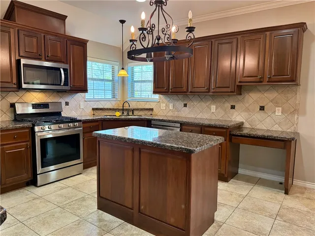 a kitchen with stainless steel appliances granite countertop wooden cabinets a stove top oven a sink and dishwasher