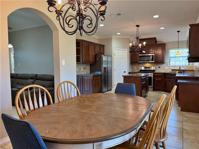 a dining room with stainless steel appliances kitchen island granite countertop a dining table chairs and a oven